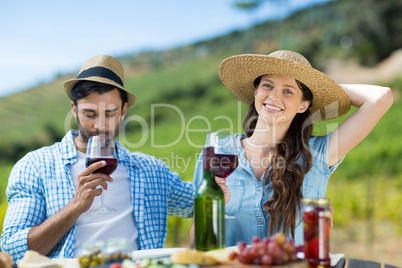 Smiling woman with red wine sitting by male friend at table