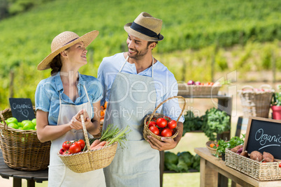 Happy couple holding fresh vegetables in baskets