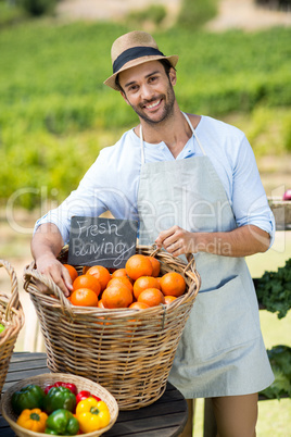 Portrait of smiling farmer standing by fresh oranges in container