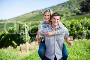 Portrait of young couple holding wineglasses while piggybacking