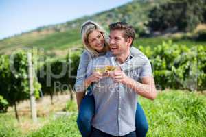 Portrait of happy couple toasting wineglasses while piggybacking