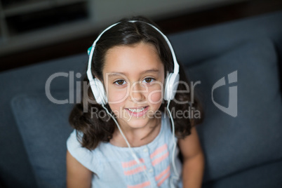 Smiling girl listening to music on headphones in living room