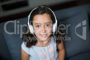 Smiling girl listening to music on headphones in living room