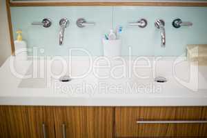 Sink faucets with hand wash, toothbrush and toothpaste in bathroom