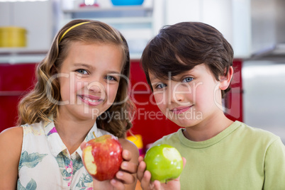 Siblings showing missing bite of apple in kitchen
