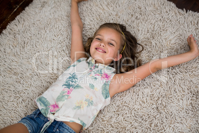 Portrait of smiling girl lying on rug in living room