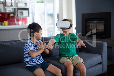 Boy looking at his brother using virtual reality headset in living room