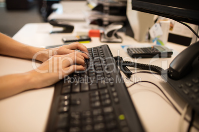 Cropped hands of businesswoman using computer keyboard at office