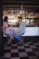 Happy couple interacting while having beer at counter