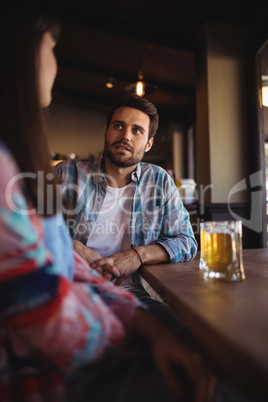 Couple interacting while having beer at counter