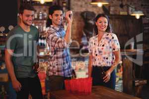 Group of happy friends playing beer pong game