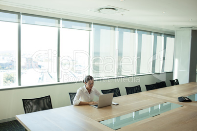 Businesswoman using laptop in conference room