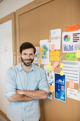 Portrait of confident businessman standing by soft board at office