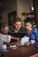 Friends using digital tablet while having breakfast