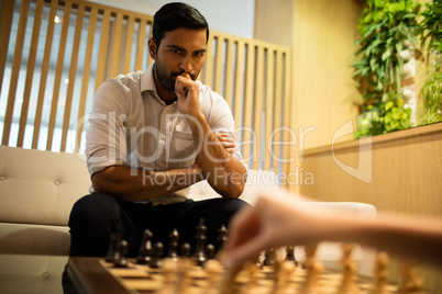 Thoughtful businessman playing chess with female colleague