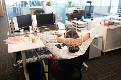 Businesswoman relaxing on chair by desk in office