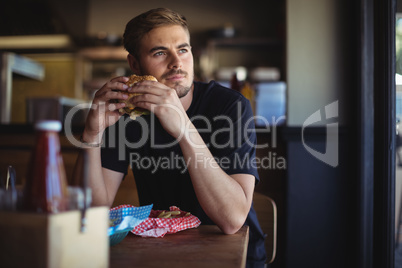 Thoughtful man holding burger