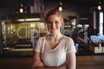Beautiful woman standing with arms crossed in restaurant