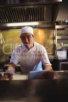 Chef holding digital tablet and an order list in the commercial kitchen