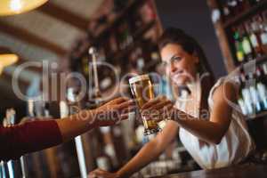 Female bar tender giving glass of beer to customer