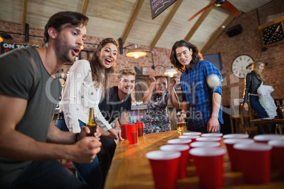 Young friends enjoying beer pong game in restaurant