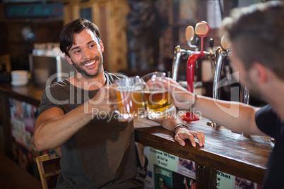 Smiling man toasting beer mug with male friend