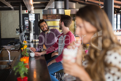 Male friends talking while sitting in restaurant