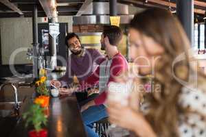 Male friends talking while sitting in restaurant