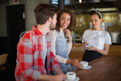 Smiling woman looking at friend while placing order to waitress