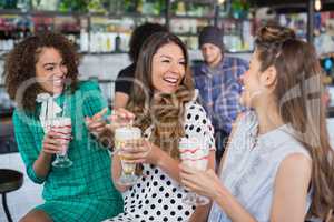 Female friends enjoying while having drink in restaurant