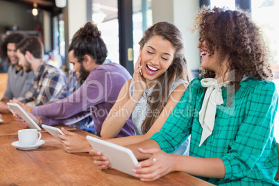 Friends using digital tablet while sitting in restaurant