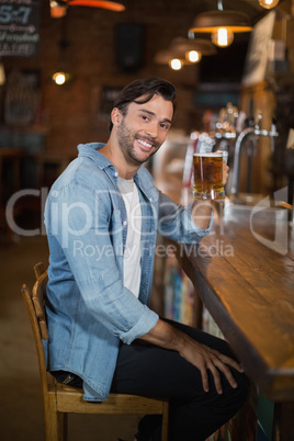 Smiling man holding beer glass at restaurant