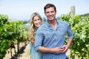 Portrait of happy young couple embracing at vineyard