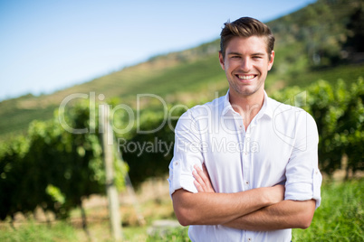 Portrait of smiling man with arms crossed standing at vineyard