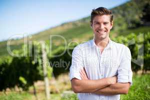 Portrait of smiling man with arms crossed standing at vineyard