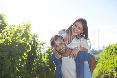 Happy young couple piggybacking during sunny day