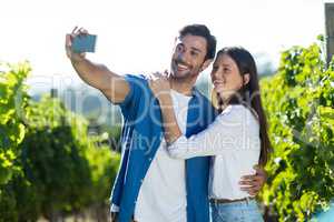 Happy young couple taking selfie at vineyard