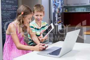 Boy showing digital tablet to girl in kitchen