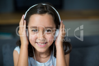 Smiling girl listening to music on headphones in living room