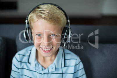 Smiling boy listening to music on headphones in living room