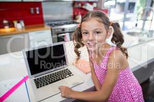 Portrait of girl using laptop in kitchen