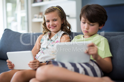 Siblings using digital tablet in living room