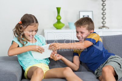 Siblings fighting over digital tablet in living room