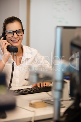 Smiling businesswoman using telephone in office