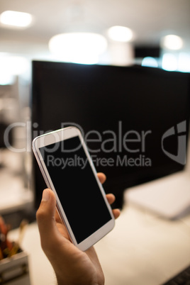 Hand of businessman holding mobile phone in office