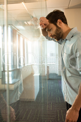 Side view of depressed businessman leaning on glass