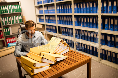 Businessman looking at stack of files on table in storage room