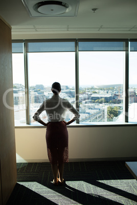 Female business executive looking through window in office