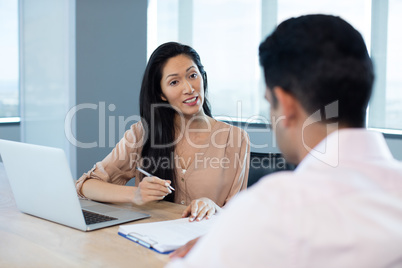 Businesswoman discussing contract with male colleague during meeting