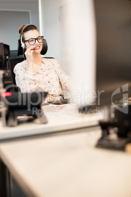 Smiling businesswoman talking on headset at office